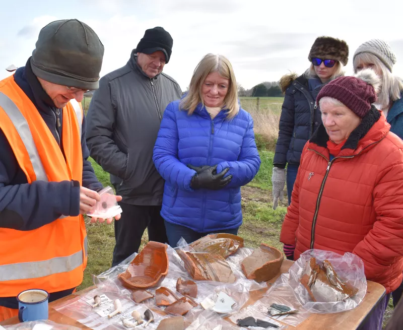An archaeologist shows artefacts to a group of visitors