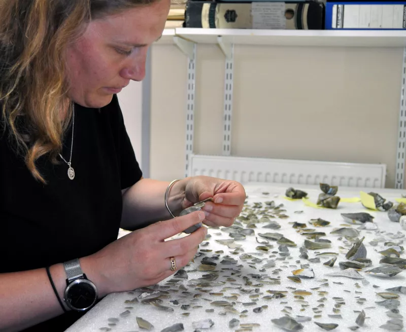 Image showing one of OA's flint specialists analysing flint tools.